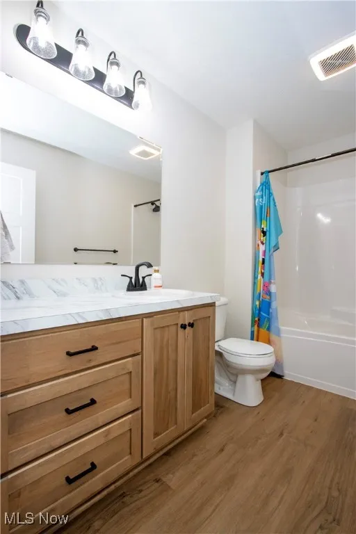 Full bathroom with light wood-type flooring, vanity, and shower / bath combo