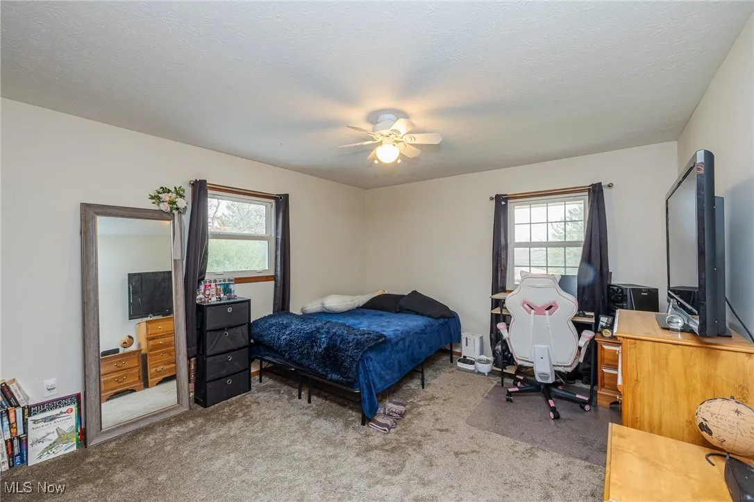 Bedroom with light carpet, multiple windows, a ceiling fan, and a textured​​‌​​​​‌​​‌‌​‌‌​​​‌‌​‌​‌​‌​​​‌​​ ceiling