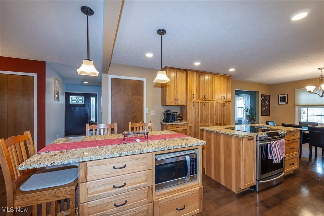 Kitchen featuring a kitchen island, a breakfast bar area, stainless steel appliances, light stone counters, and recessed lighting
