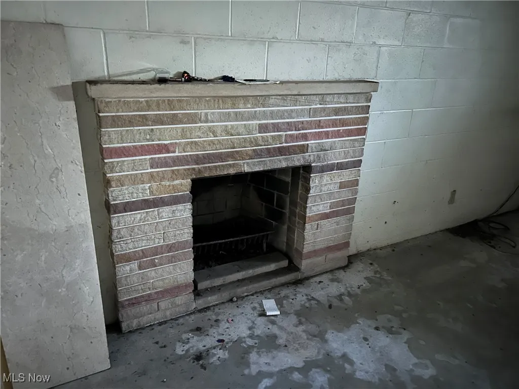 Detailed view of concrete floors, a brick fireplace, and concrete block wall