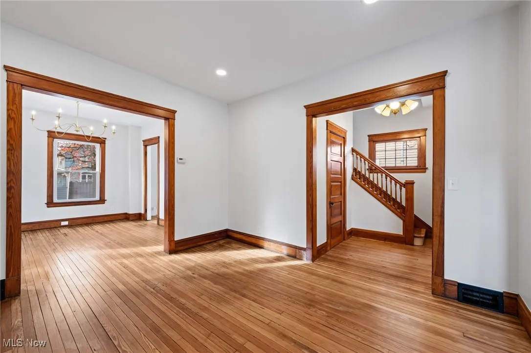 Living room with a chandelier, light wood-style flooring, recessed lighting, and stairs