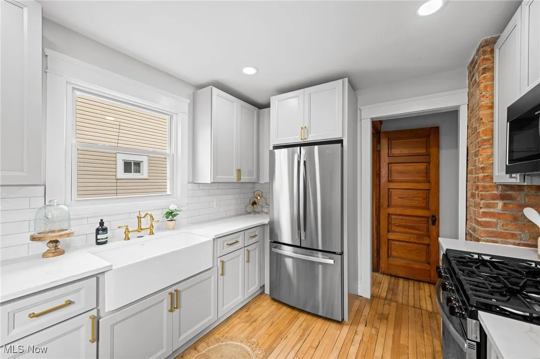 Kitchen with stainless steel appliances, light wood floors, light stone countertops, white cabinetry, and recessed lighting