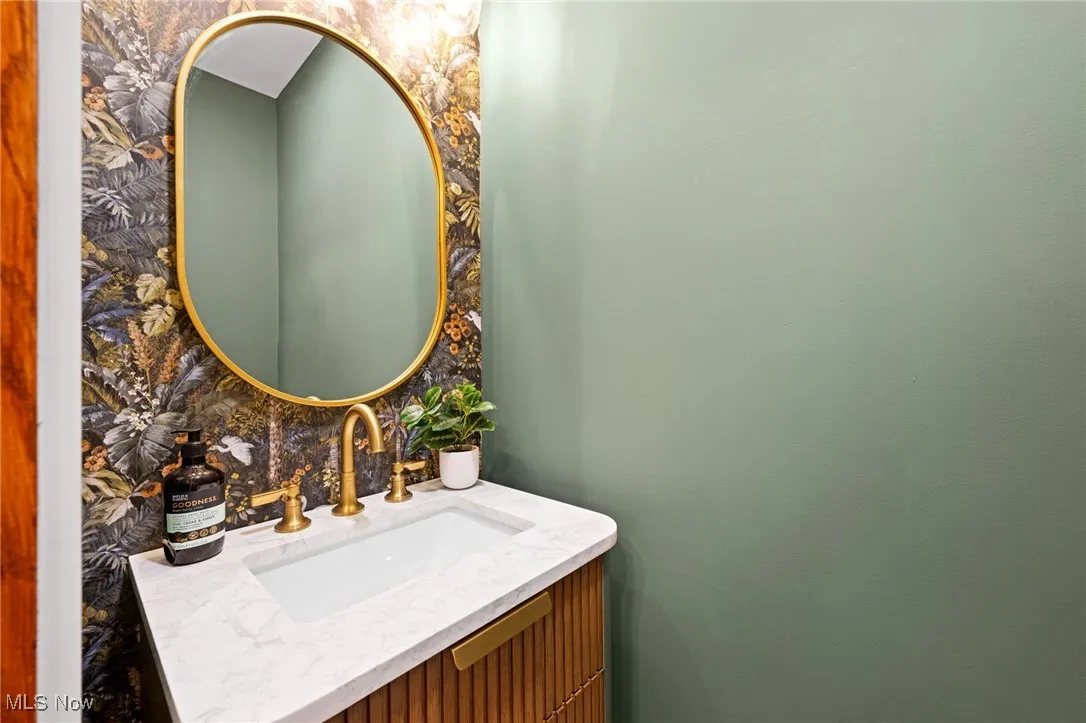 Bathroom featuring vanity, backsplash, and wallpapered walls