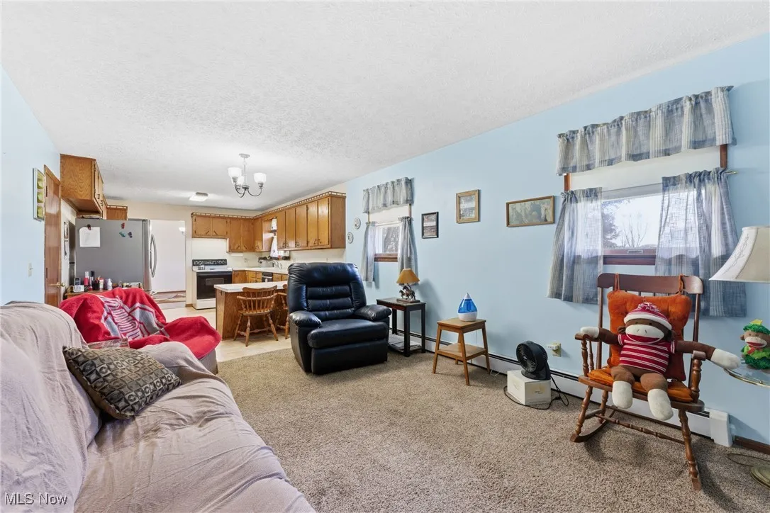 Living area with a textured ceiling, light carpet, and a chandelier