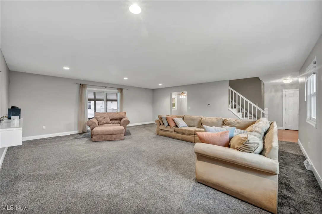 Carpeted living room featuring recessed lighting and stairs
