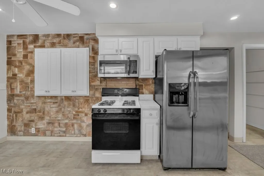 Kitchen with stainless steel appliances, white cabinetry, recessed lighting, and a ceiling fan