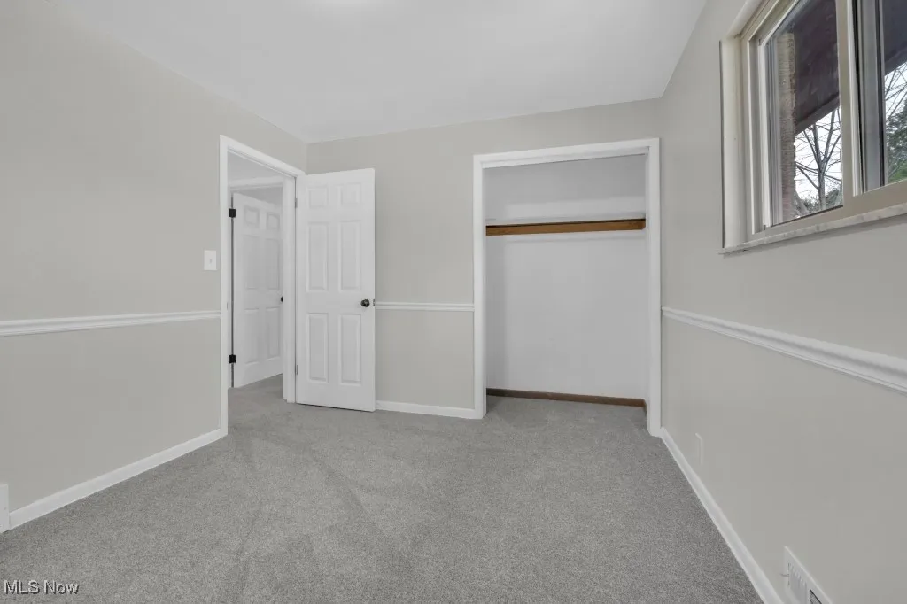 Unfurnished bedroom with light carpet and a closet