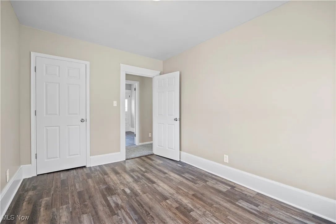 Unfurnished bedroom with dark wood-type flooring and baseboards