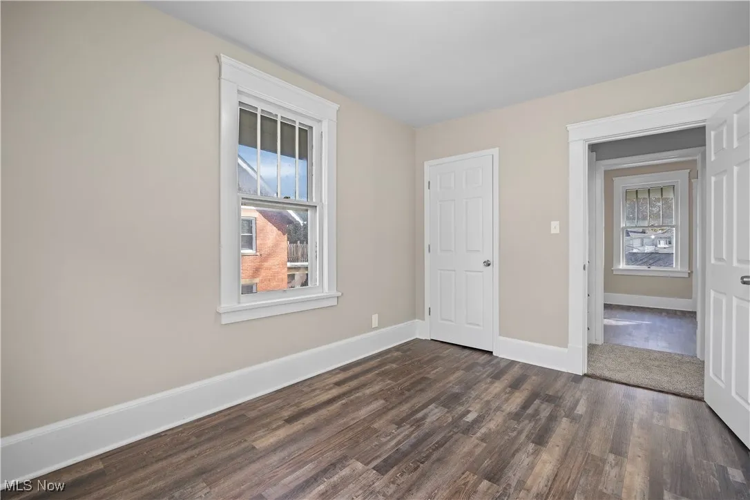 Unfurnished bedroom with baseboards and dark wood-style flooring