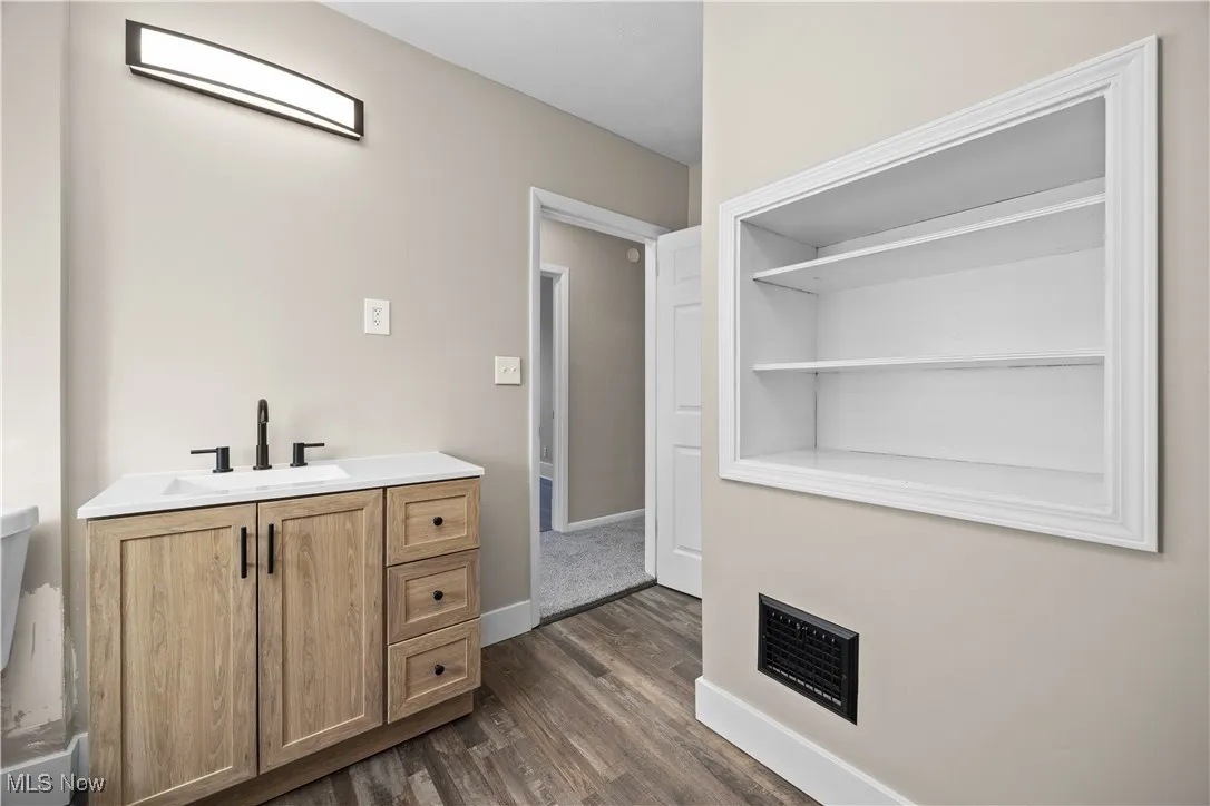 Half bath with vanity and dark wood finished floors