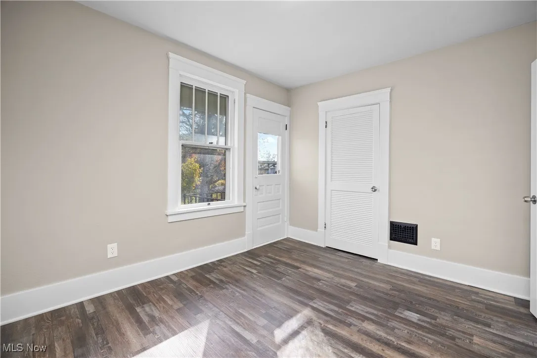 Empty room with baseboards and dark wood-style floors