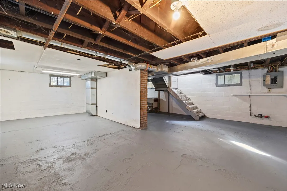 Basement featuring electric panel and stairway