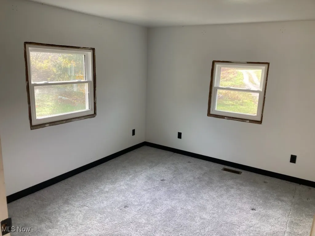 Spare room featuring baseboards and light colored carpet