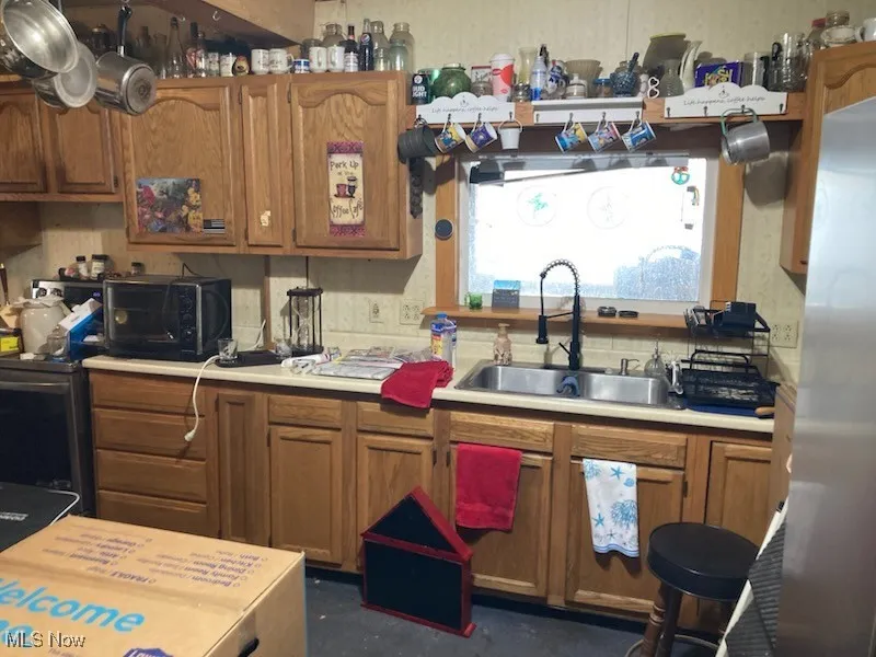 Kitchen featuring brown cabinetry, light countertops, and stainless steel appliances