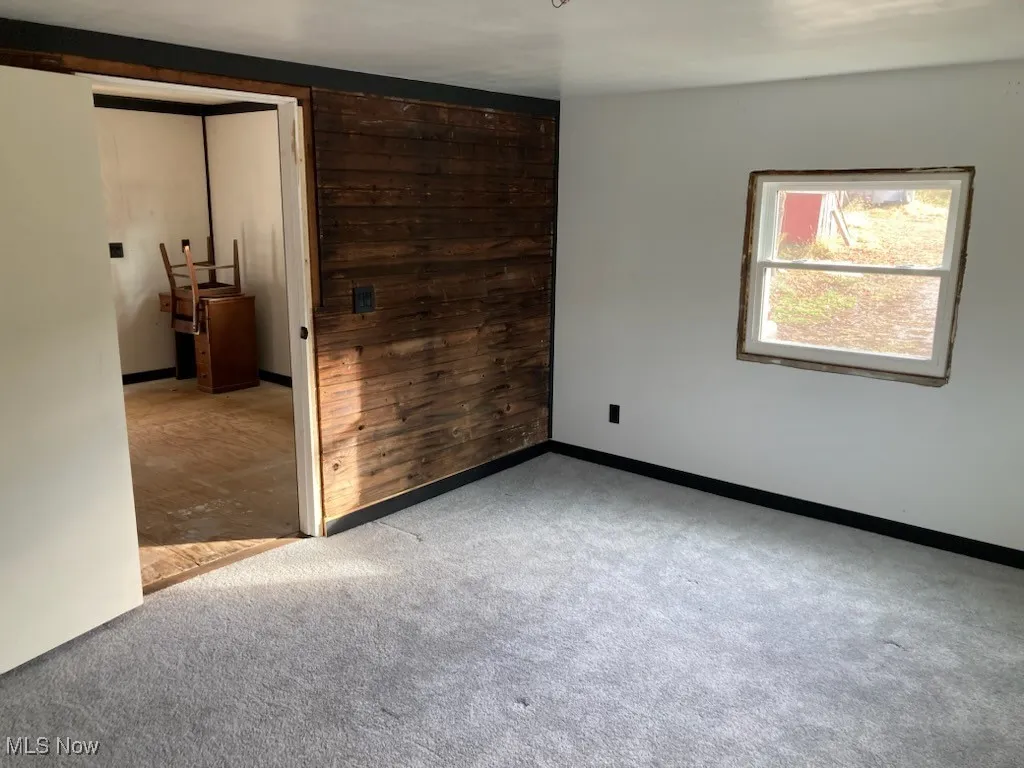 Unfurnished bedroom featuring wood walls and light carpet