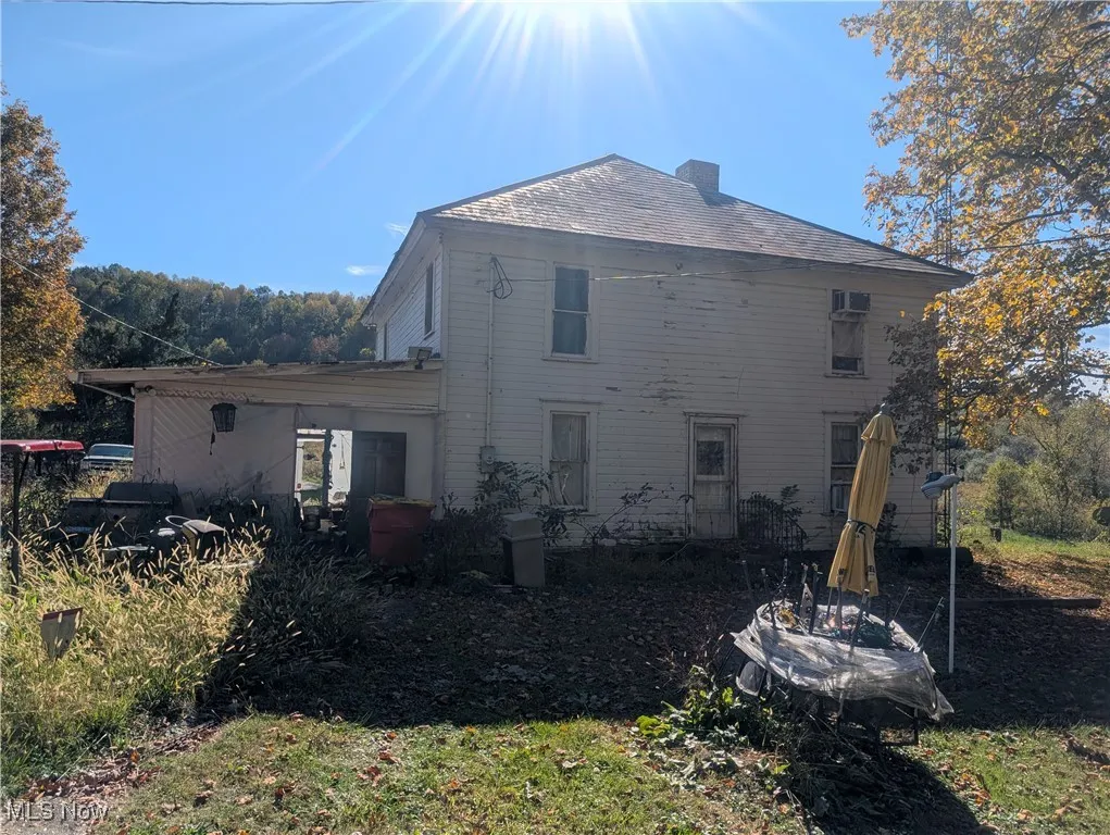 Rear view of property featuring a chimney and roof with shingles