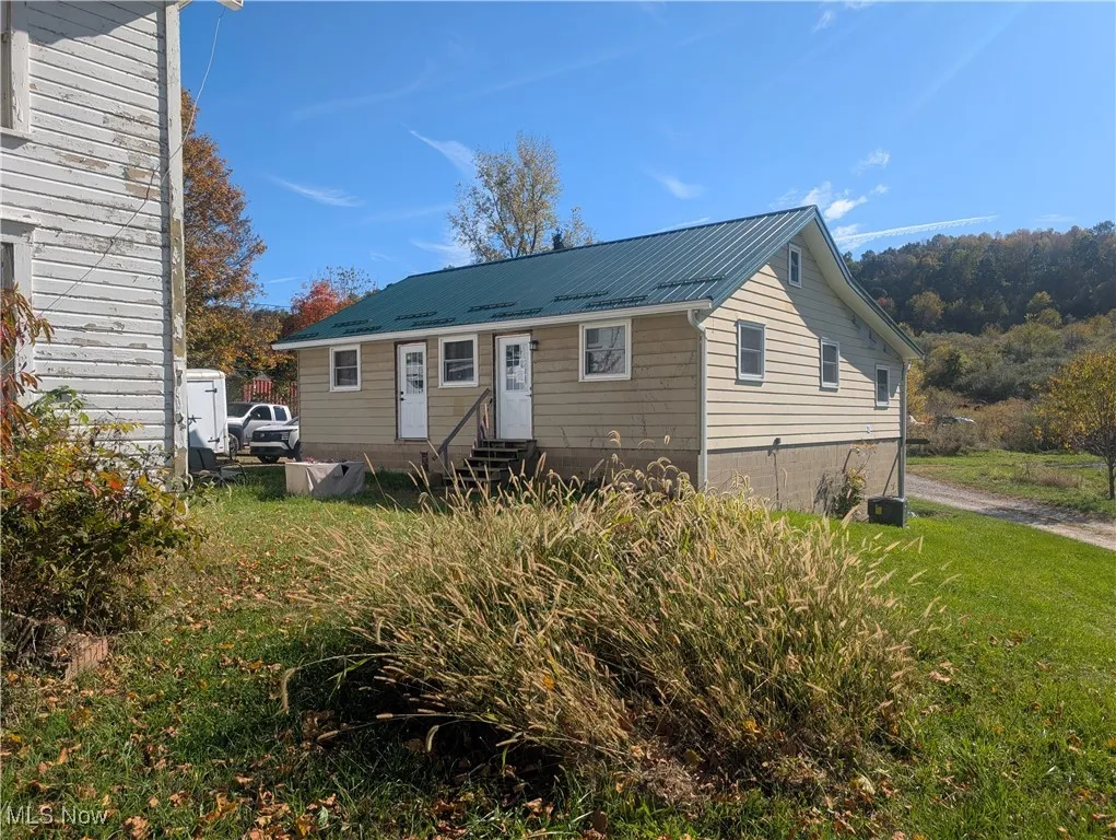 View of front of house featuring entry steps, a metal roof, and a front lawn