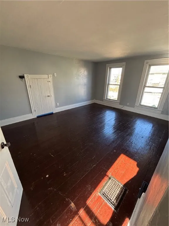 Unfurnished room with dark wood finished floors and baseboards