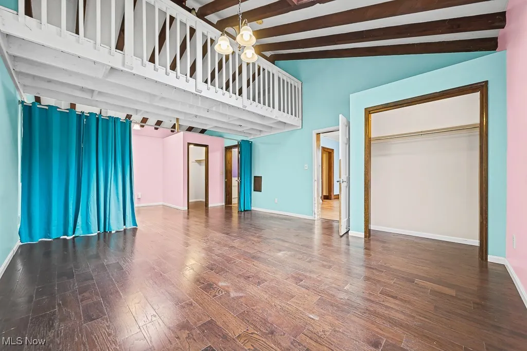 Unfurnished bedroom with dark wood finished floors and a chandelier