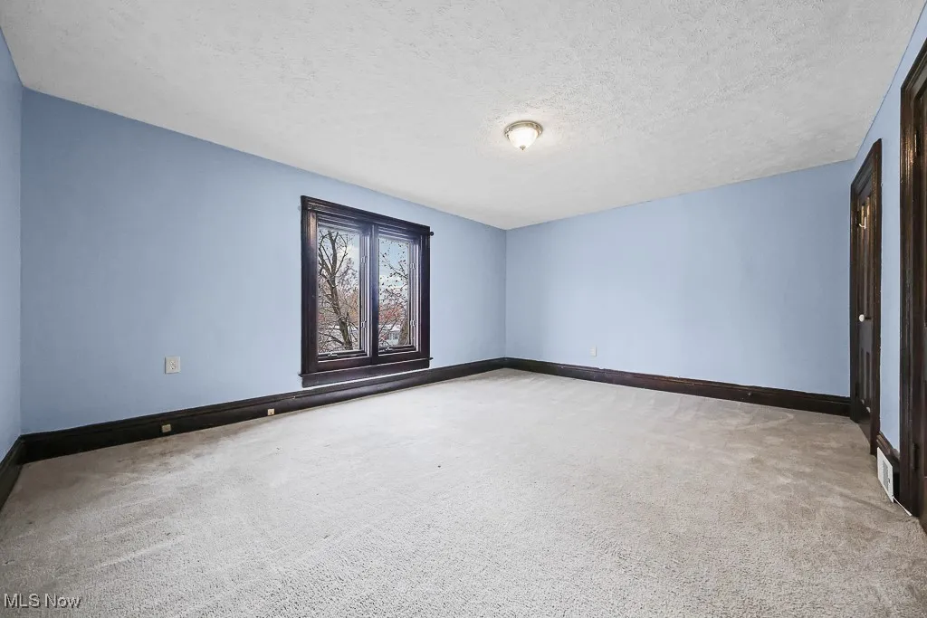Empty room featuring a textured ceiling and light colored carpet