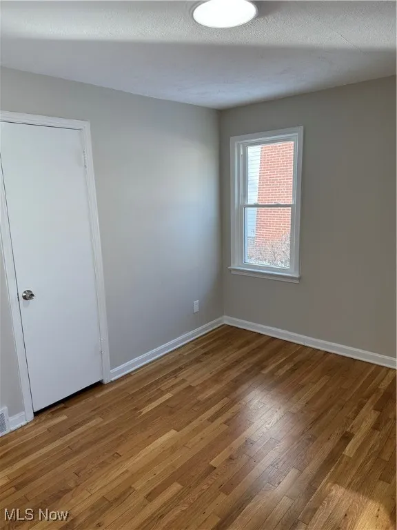 Unfurnished room with hardwood / wood-style floors and a textured ceiling