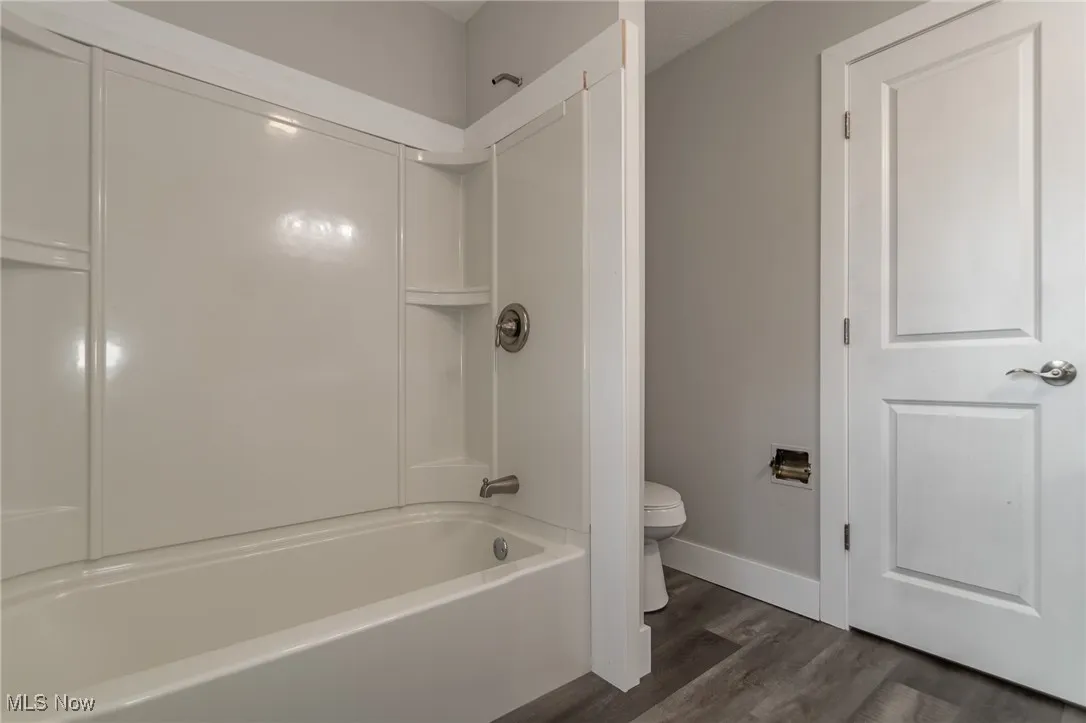 Full bathroom featuring dark wood-style floors and washtub / shower combination