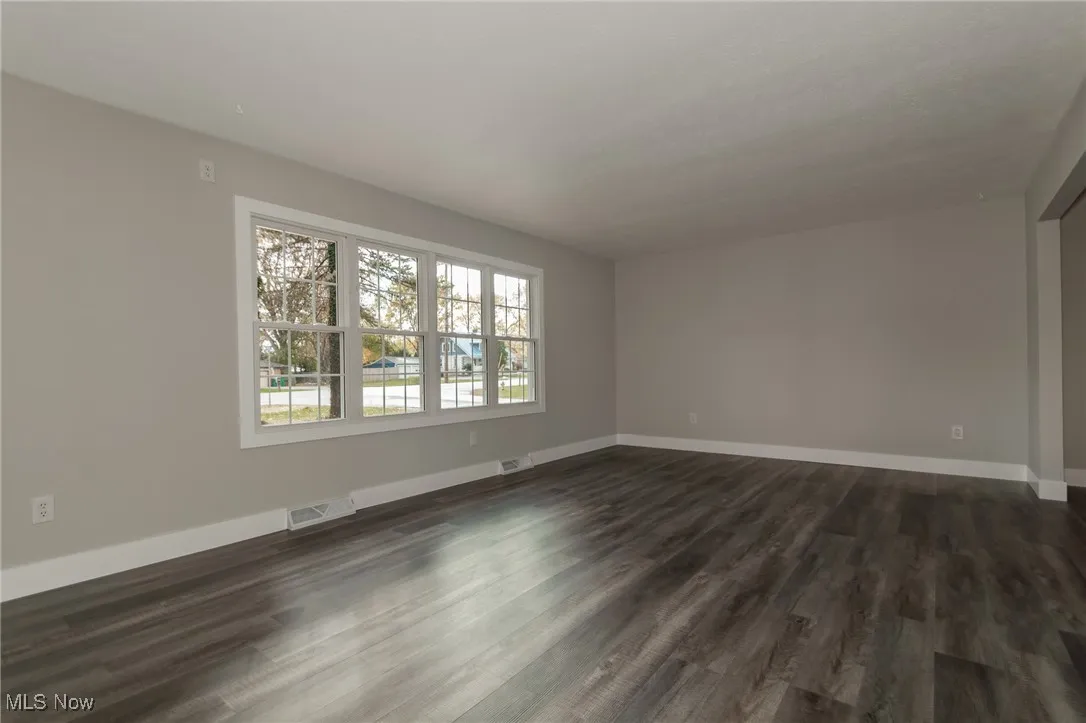 Spare room featuring dark wood-type flooring and baseboards