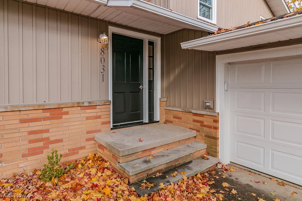 Property entrance with a garage and board and batten siding