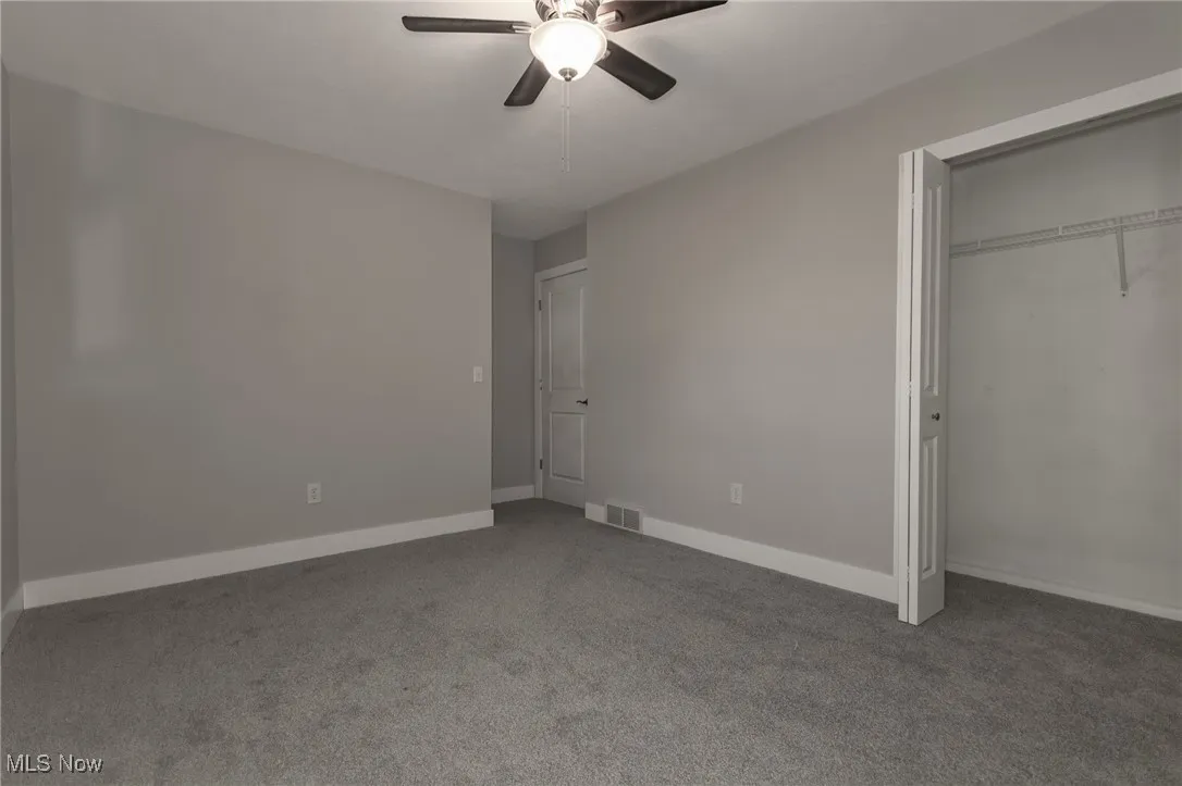 Unfurnished bedroom with carpet, a closet, and ceiling fan