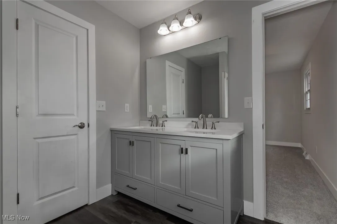 Bathroom featuring baseboards and double vanity