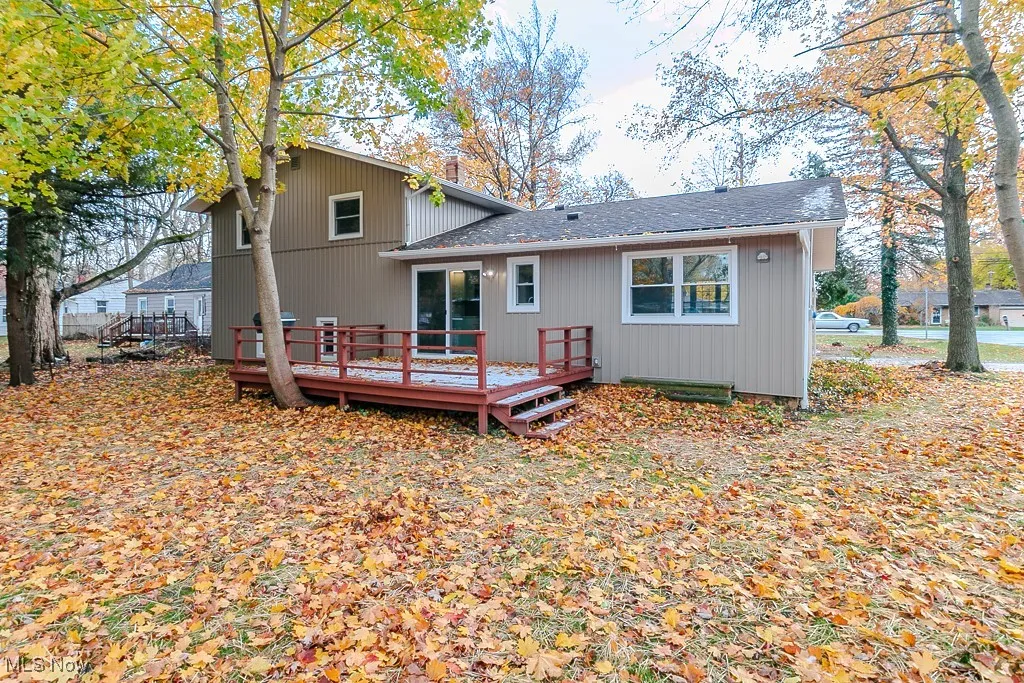 Back of property with a wooden deck and roof with shingles