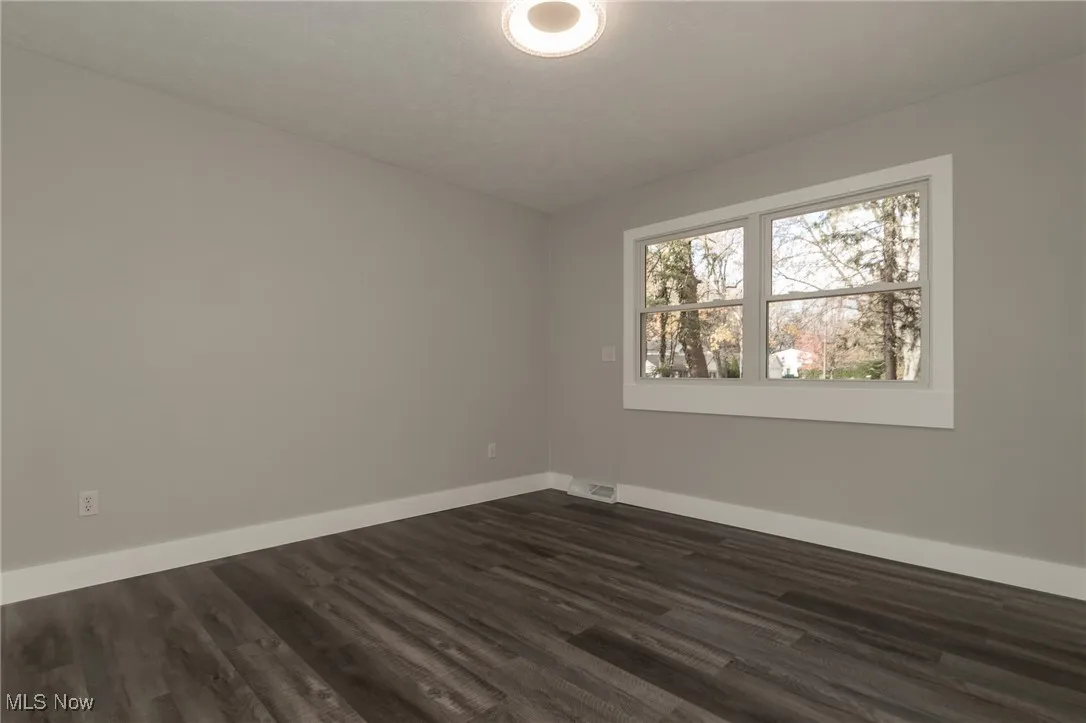 Spare room featuring dark wood finished floors and baseboards