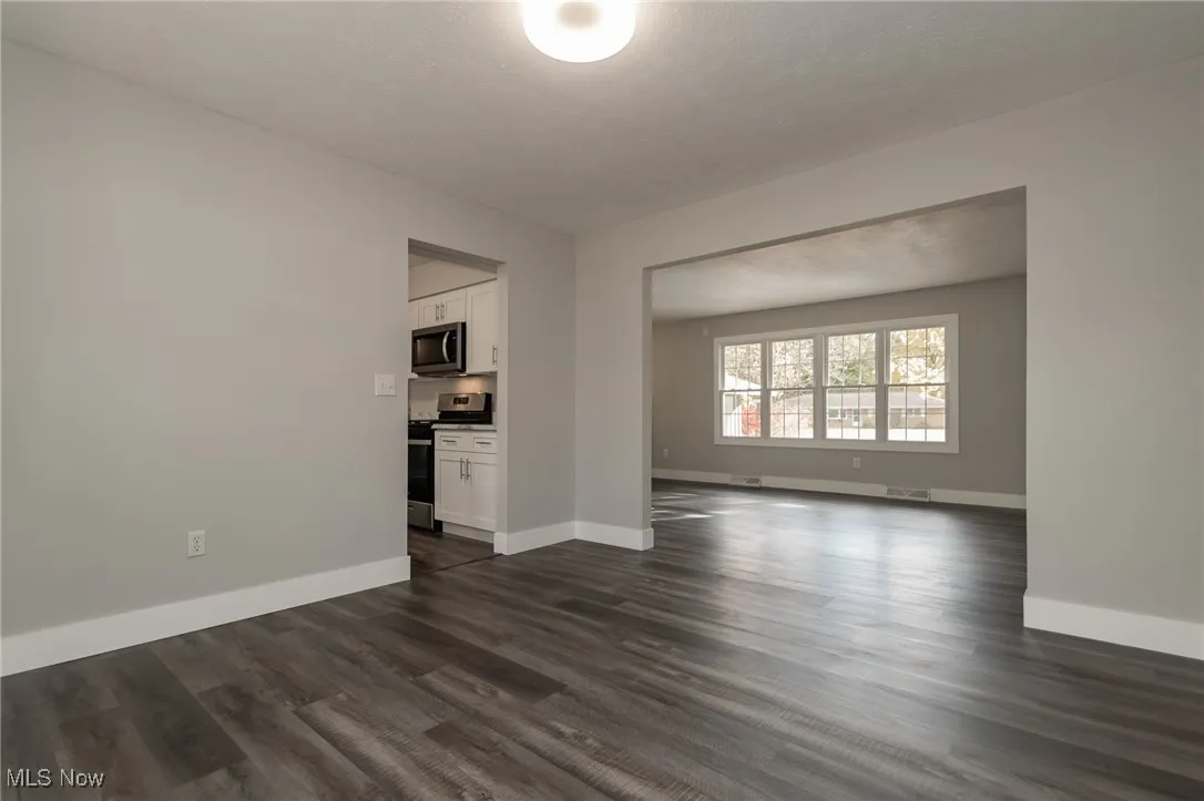 Unfurnished living room with dark wood finished floors and baseboards