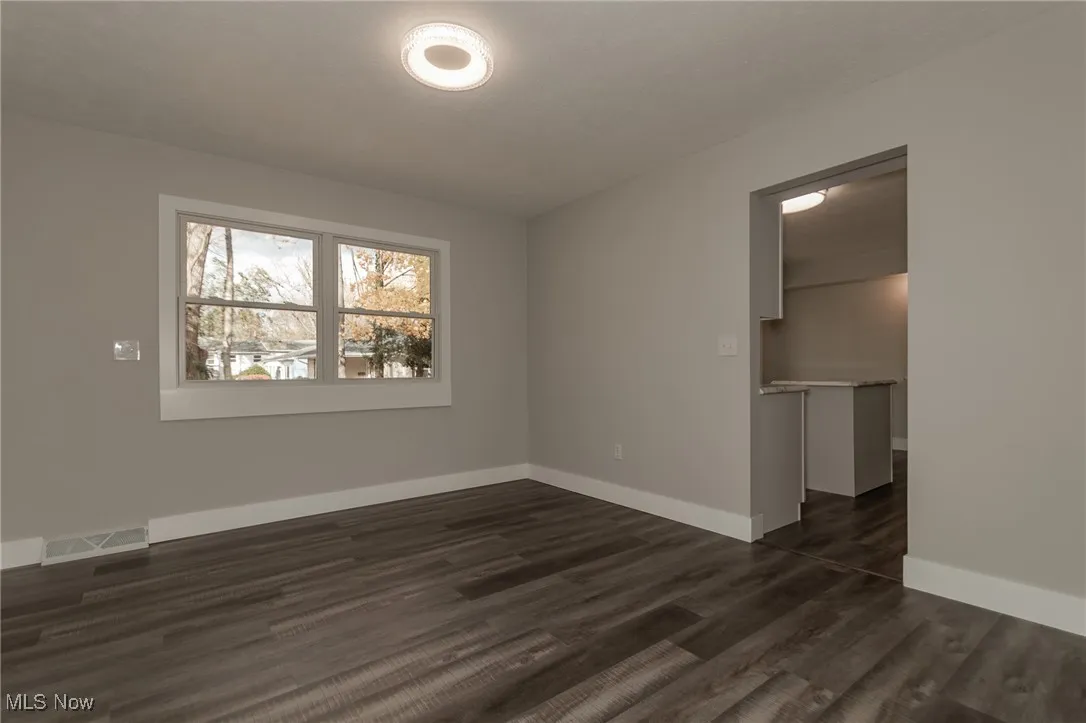 Spare room featuring baseboards and dark wood-type flooring