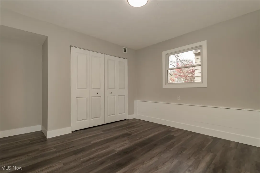 Unfurnished bedroom with dark wood finished floors and a closet