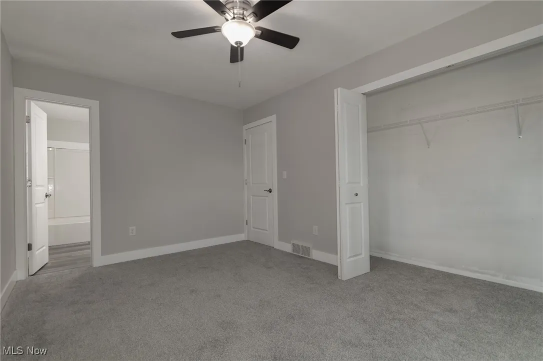 Unfurnished bedroom featuring light colored carpet, ceiling fan, a closet, and ensuite bathroom