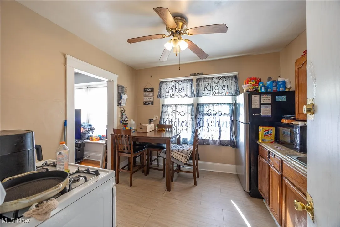 Upper unit kitchen with healthy amount of natural light, brown cabinetry, black microwave, and white range with gas cooktop