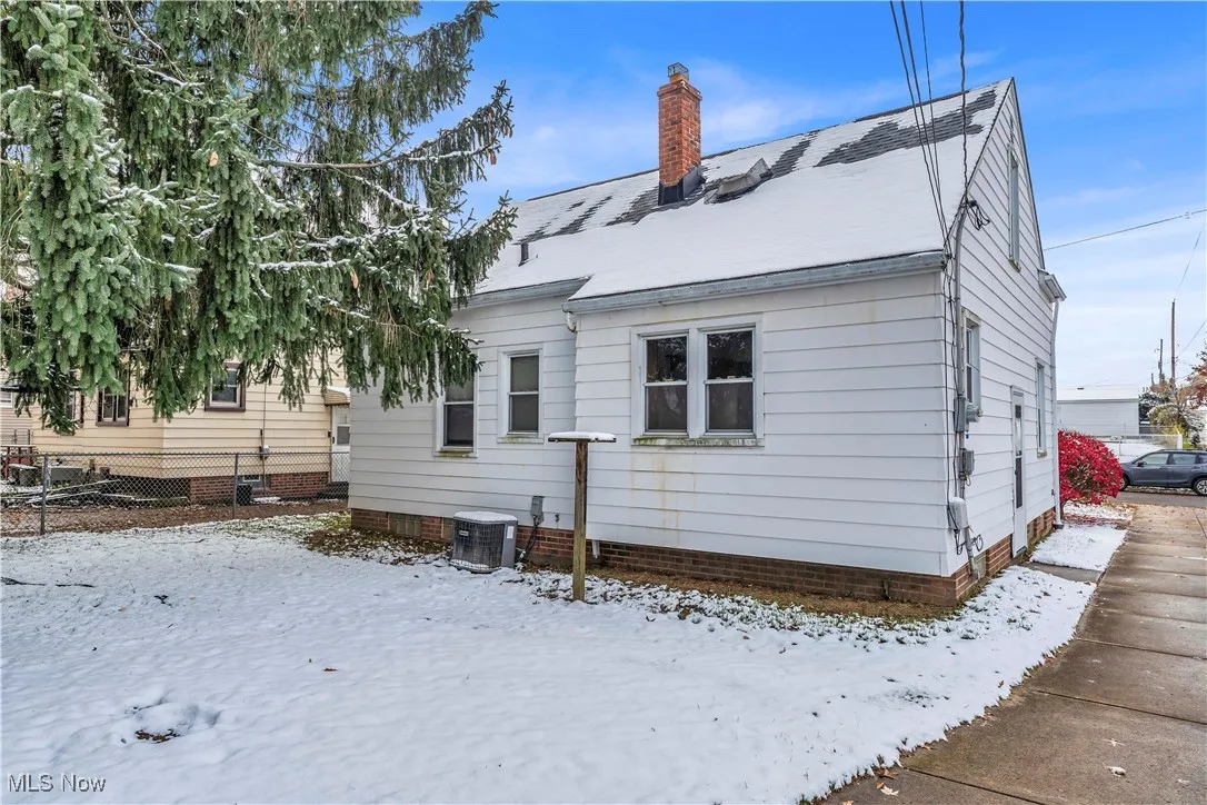 Snow covered property featuring a chimney and a shingled roof