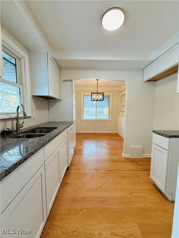 Kitchen featuring white cabinetry, light wood-style flooring, and dark stone countertops
