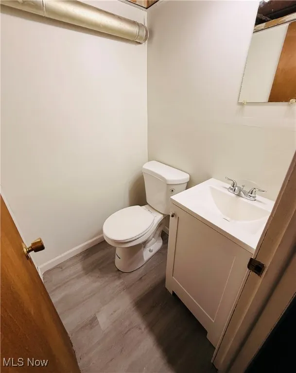 Half bathroom featuring vanity and dark wood finished floors
