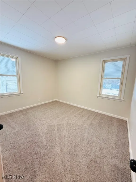 Carpeted spare room featuring baseboards