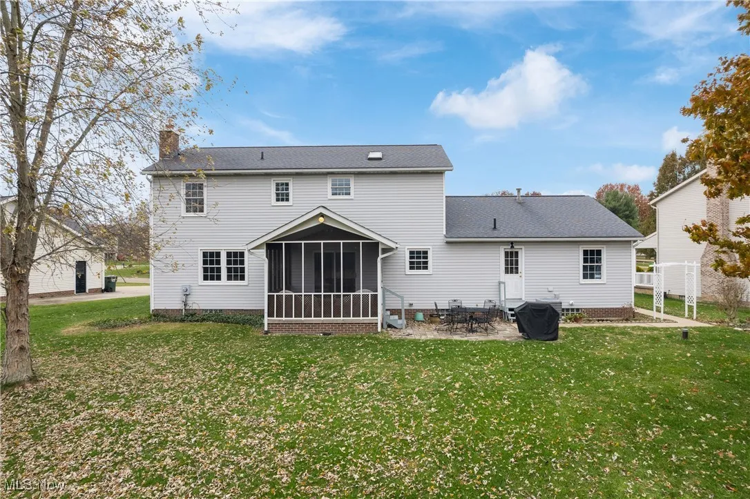 Rear view of house with a sunroom, a lawn, a patio area, a chimney, and roof with shingles