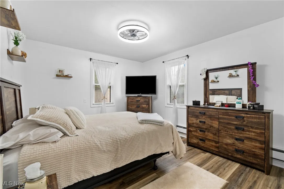Bedroom featuring wood finished floors and a baseboard heating unit