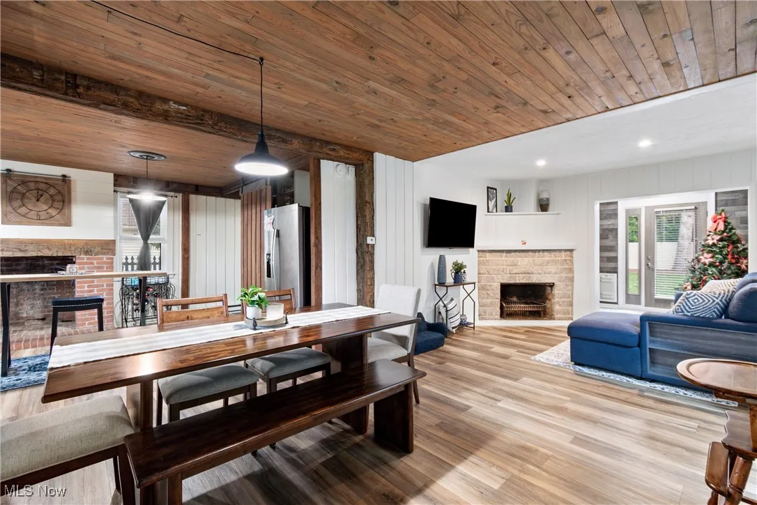 Dining room with a fireplace, light wood-style floors, wood walls, wooden ceiling, and recessed lighting