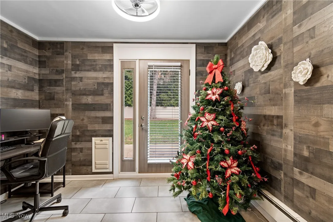 Office with tile patterned floors, a baseboard radiator, wooden walls, heating unit, and crown molding