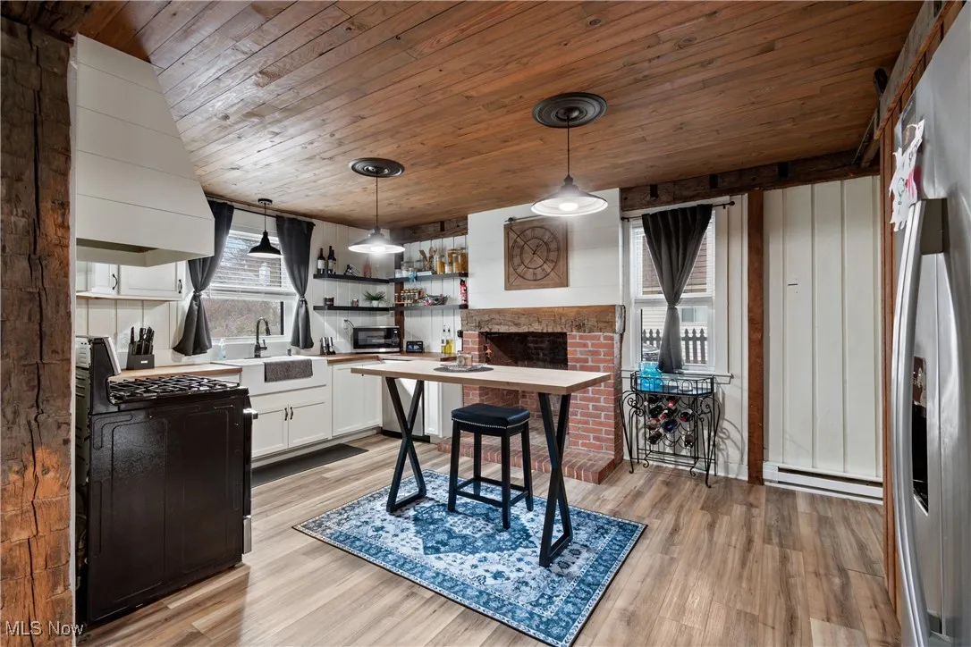 Kitchen featuring white cabinetry, open shelves, decorative light fixtures, black appliances, and light wood finished floors