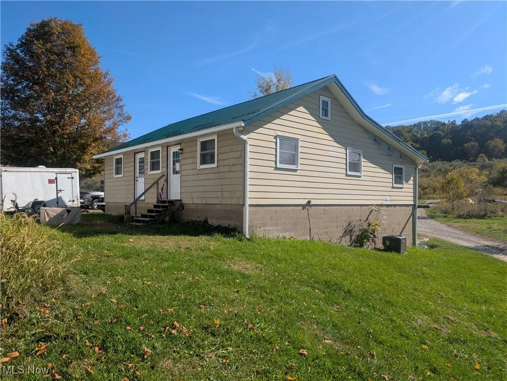 View of front facade with entry steps, a metal roof, and a front lawn