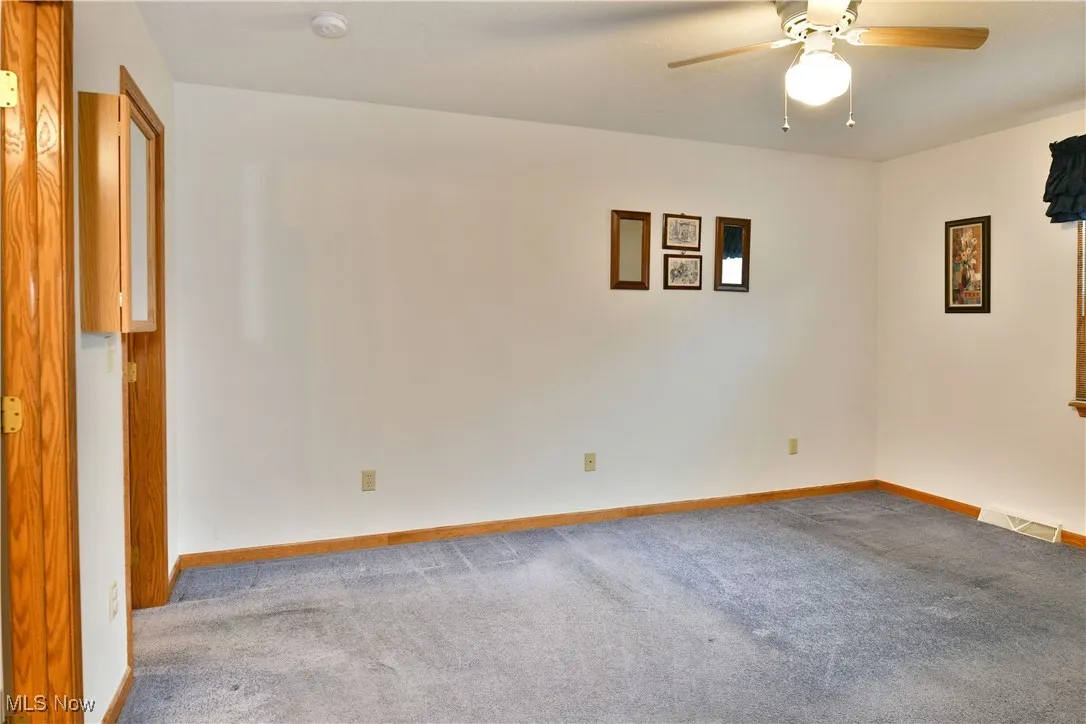 Empty room featuring carpet flooring and ceiling fan
