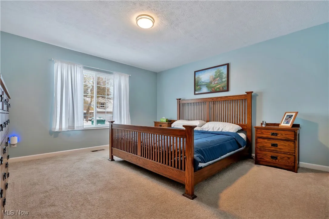 Carpeted bedroom featuring baseboards and a textured ceiling