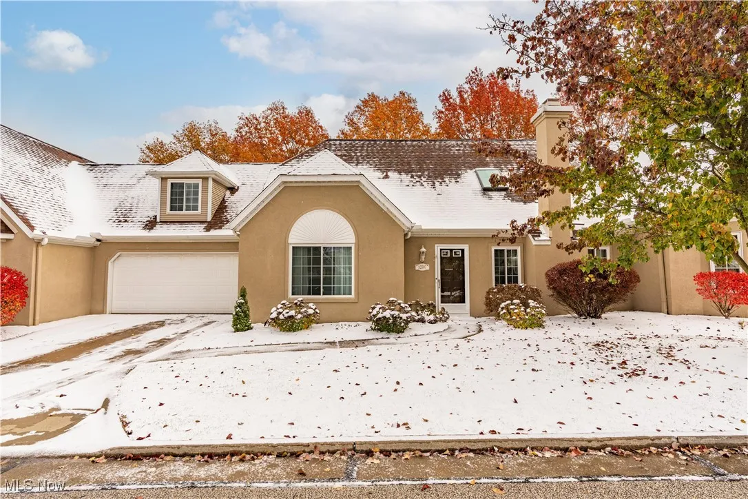 Traditional-style house featuring stucco siding, a garage, a chimney, and driveway